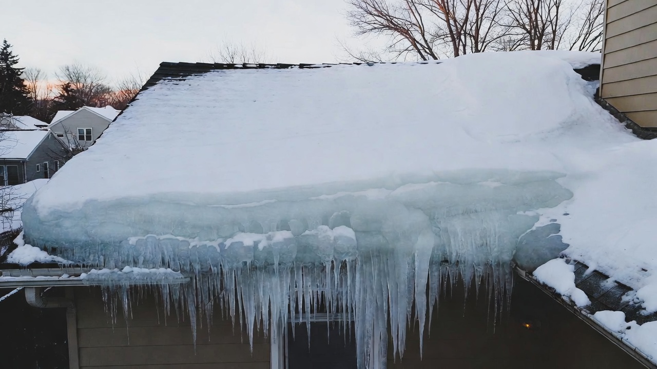 Icicles and heavy ice buildup along the eave of a home in winter